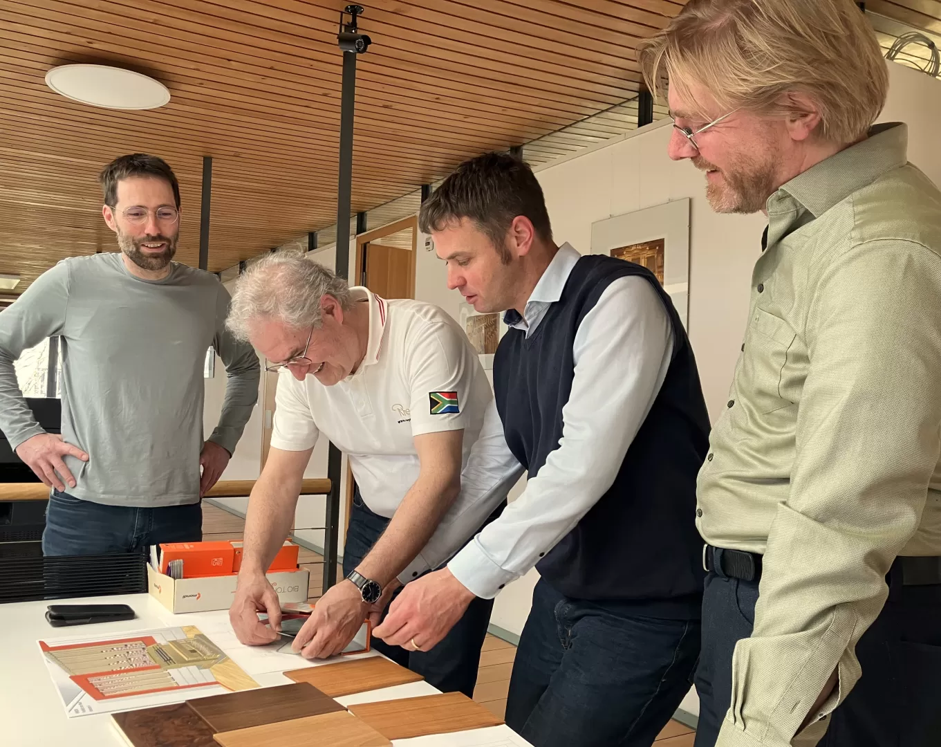 Zwei Rieger-Mitarbeiter und die beiden HfMDK-Professoren in einer Besprechung. Sie schauen sich die Skizzen der Orgel über einen Tisch gebeugt an.