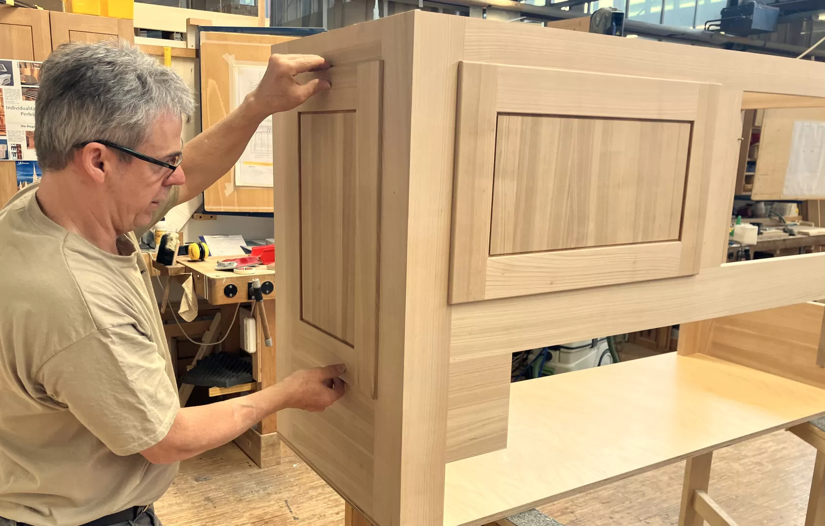 Ein Mitarbeiter setzt weitere Holzteile in die Aussparungen im Gehäuse ein.