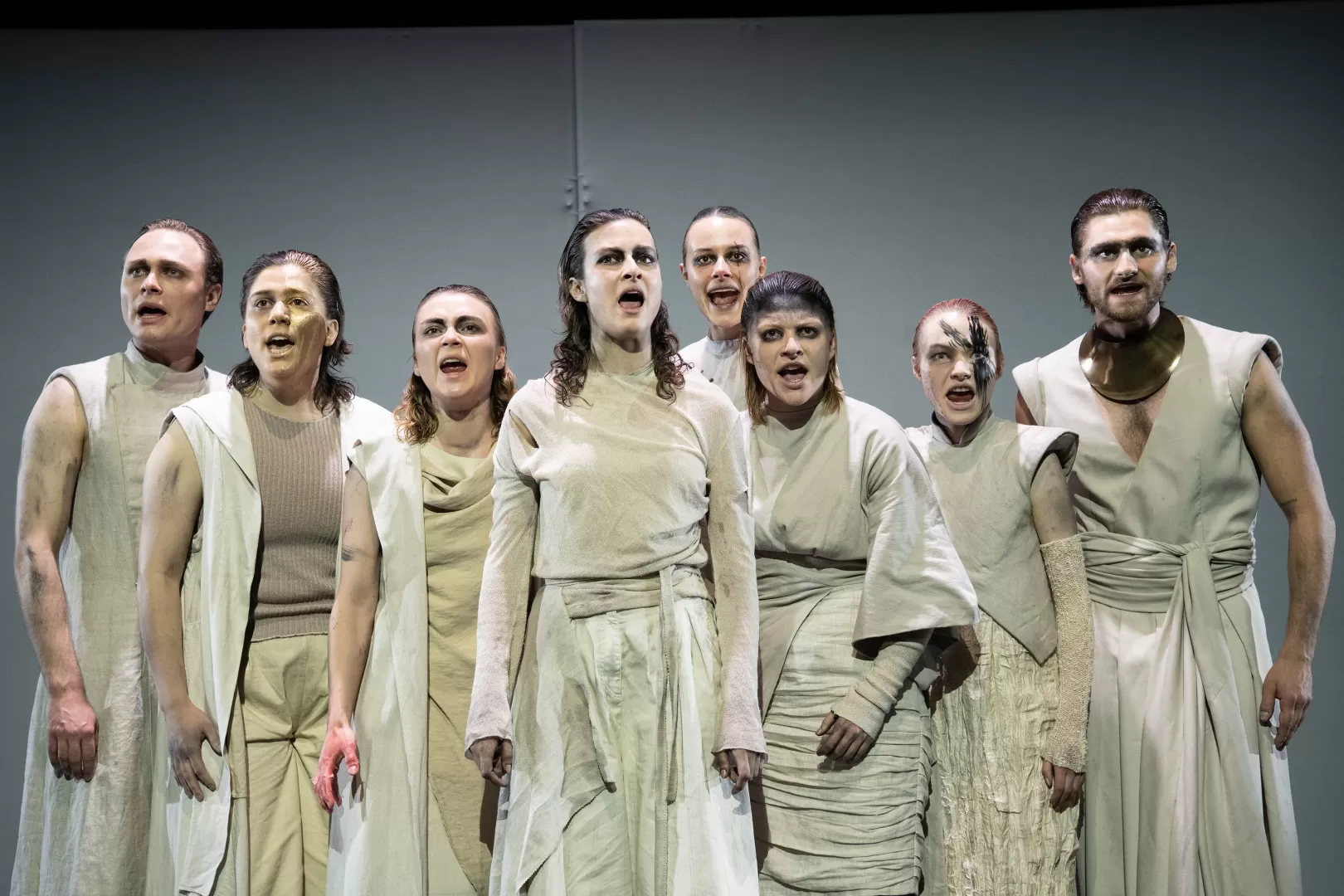 Acht Performer*innen stehen in einer Reihe, die Münder zum lauten Schrei geöffnet