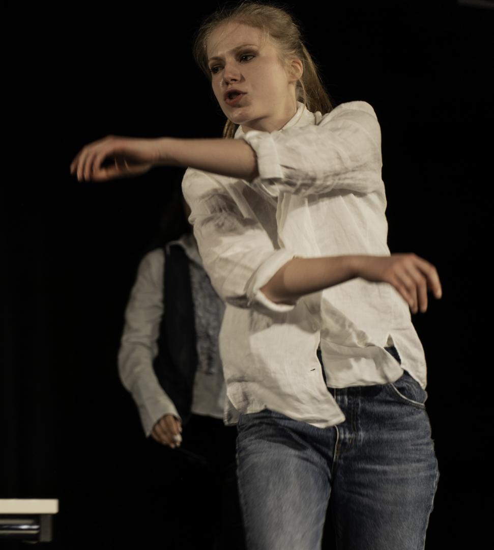 eine junge blonde Frau läuft nach vorne, ihre Arme kreuzen sich im Laufen in der Luft.
