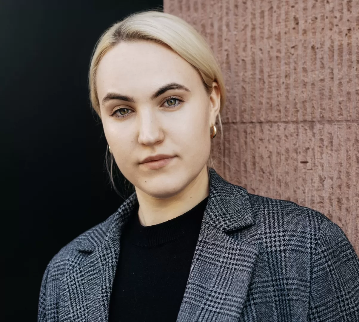Frau in einer grauen Jacke mit dem ernsten Blick und zurückgekämmten Haaren