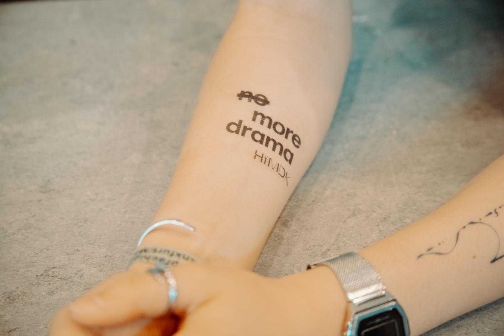 Nahaufnahme des temporären "No more drama" Tattoos auf dem Unterarm einer Person.