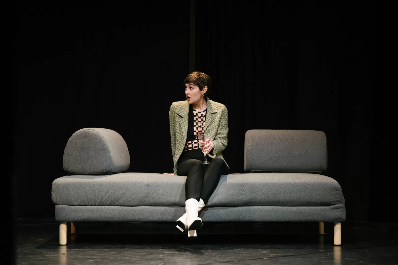 Eine Frau sitzt mit einem Glas Sekt auf einem Sofa.