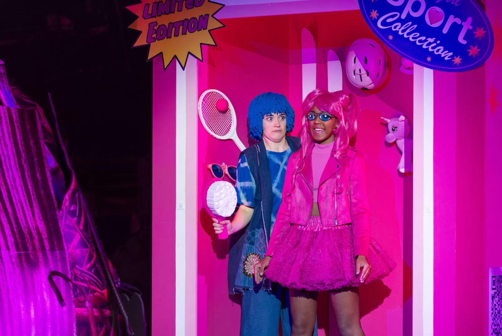 Mädchen steht neben einer großen pinken Puppe.