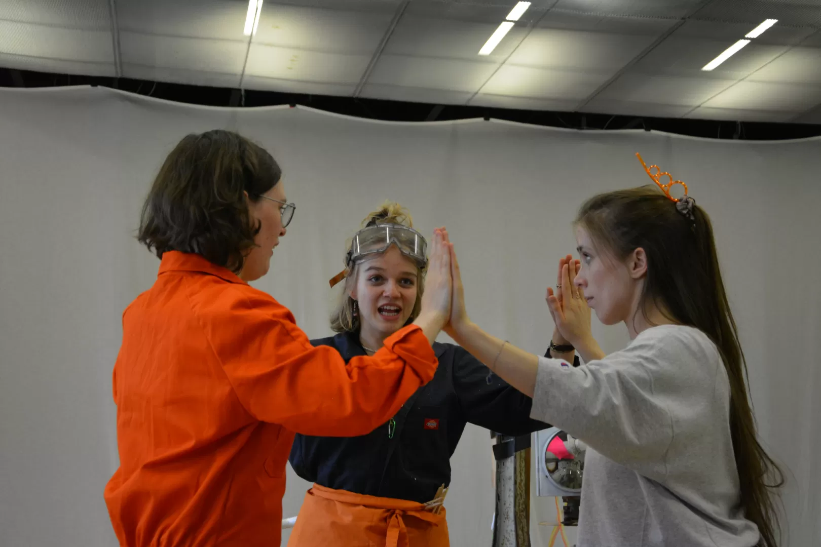 Probenfoto: Drei Darstellerinnen stehen im Kreis und drücken ihre Handflächen aneinander.