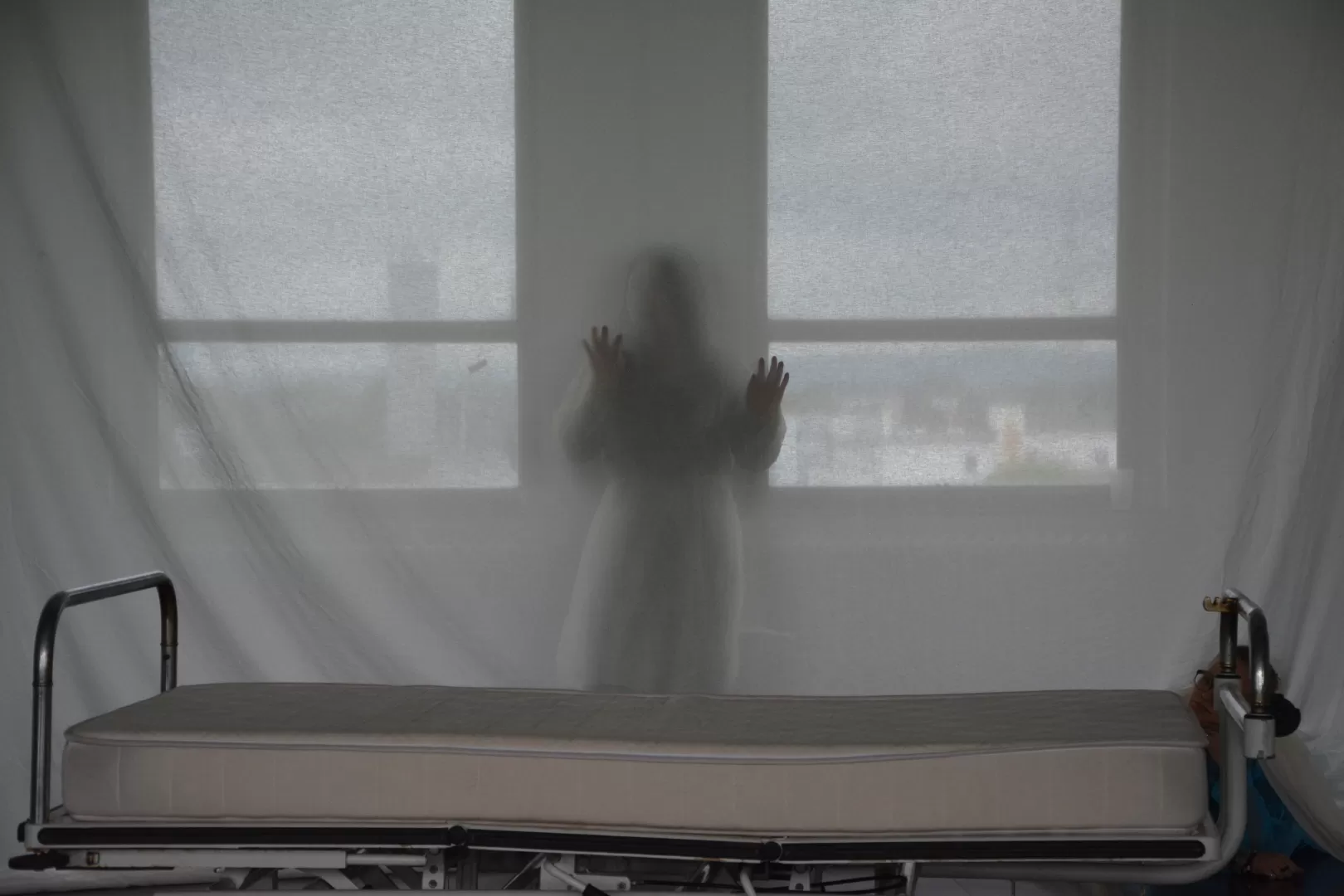 Eine Person steht hinter einer halbdurchsichtigen Leinwand.