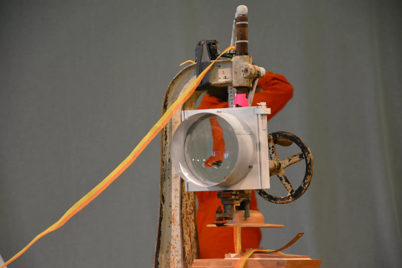 Ein Stück Bühnenbild der "Moira"-Inszenierung. Durch eine runde Linse sieht man die Darstellerin dahinter auf dem Kopf.