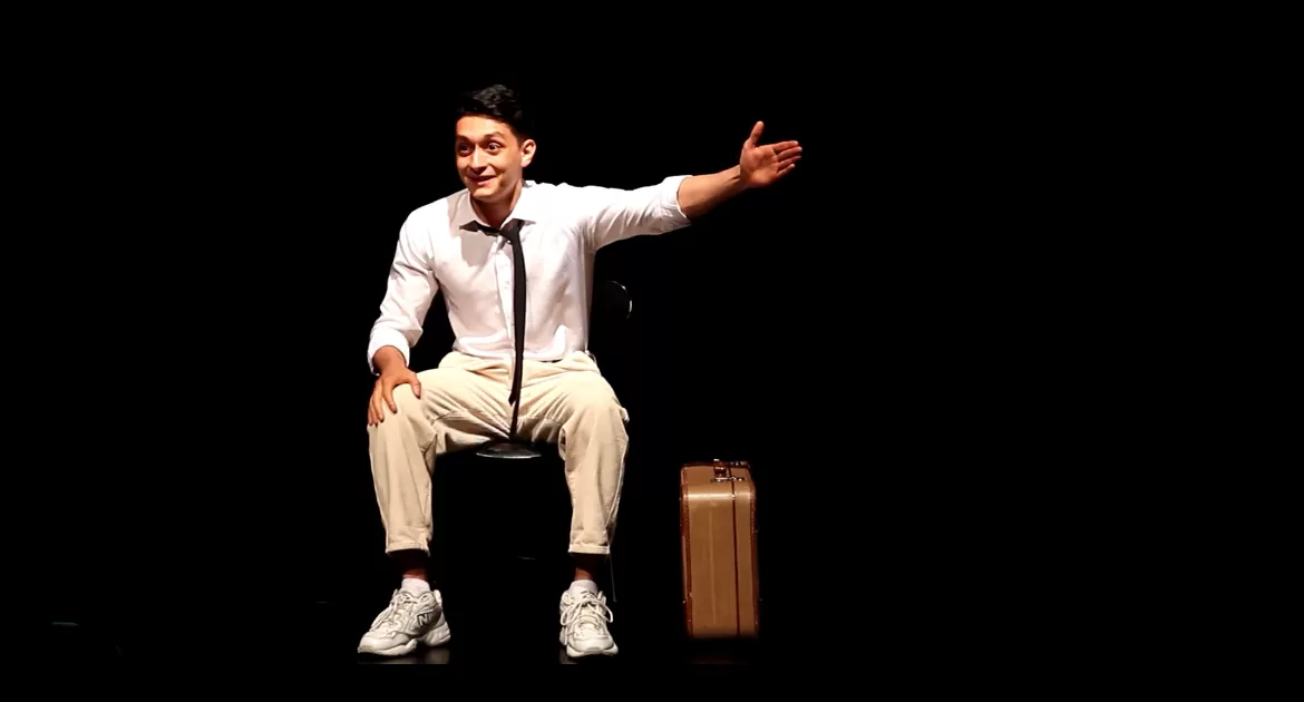 Mann mit Koffer sitzt auf einem Stuhl.