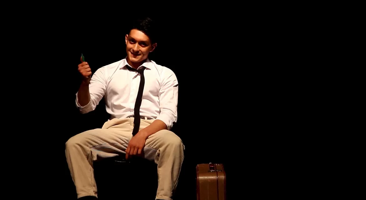 Mann mit Koffer sitzt auf einem Stuhl.