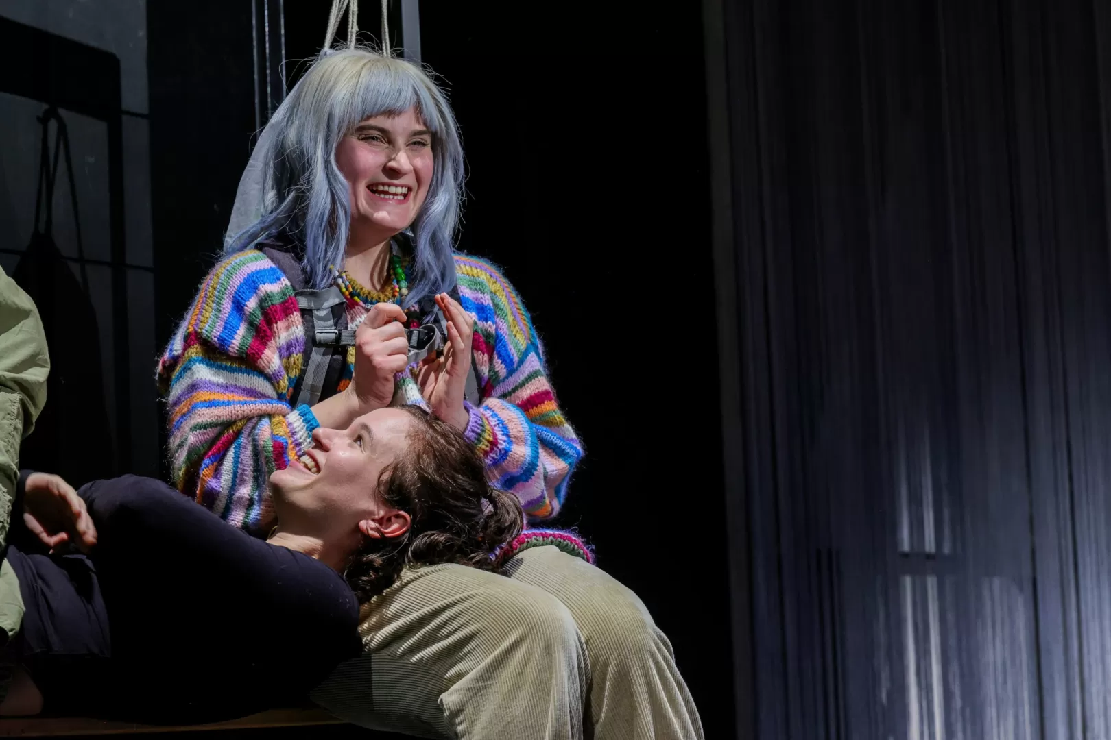 Eine Frau sitzt und eine andere Frau liegt mit dem Kopf auf ihrem Schoß.