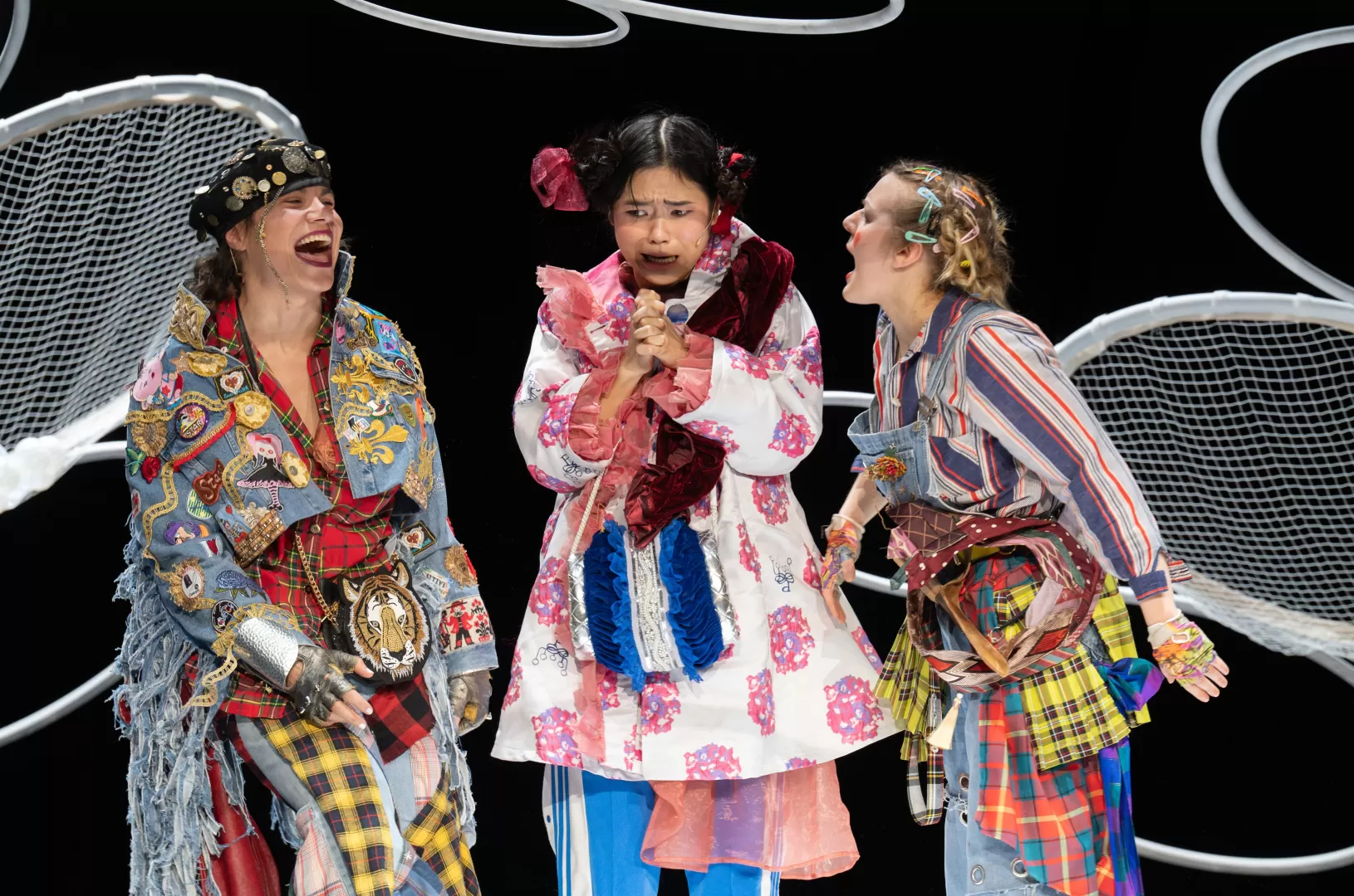 Drei Menschen, bunt angezogen, lachen einander an