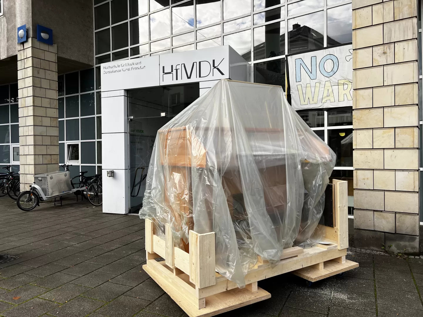 Der Spieltisch steht, unter einer Plane verpackt, vor dem Haupteingang der HfMDK.