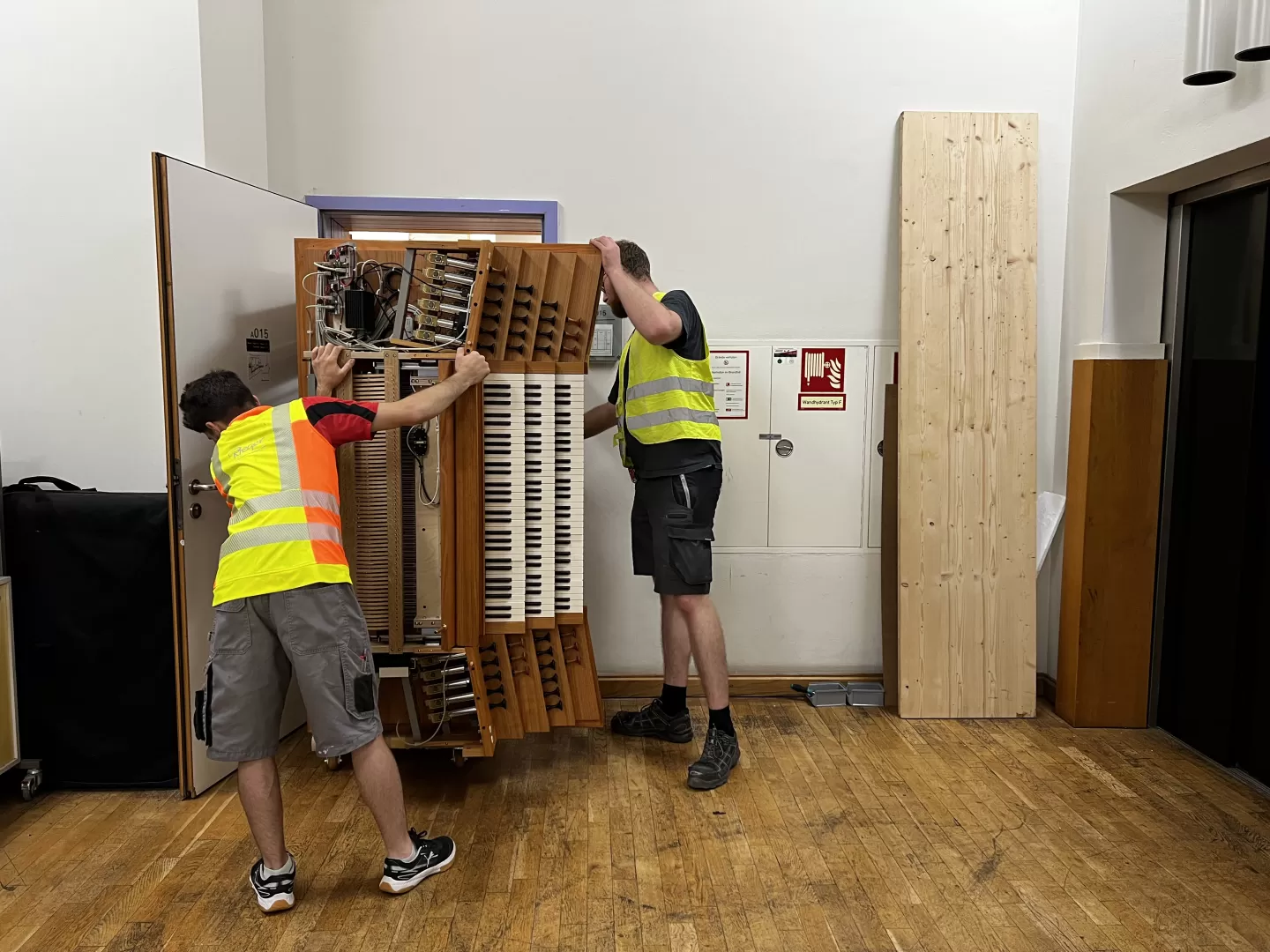 Die Handwerker schieben den Spieltisch hochkant durch die enge Tür.