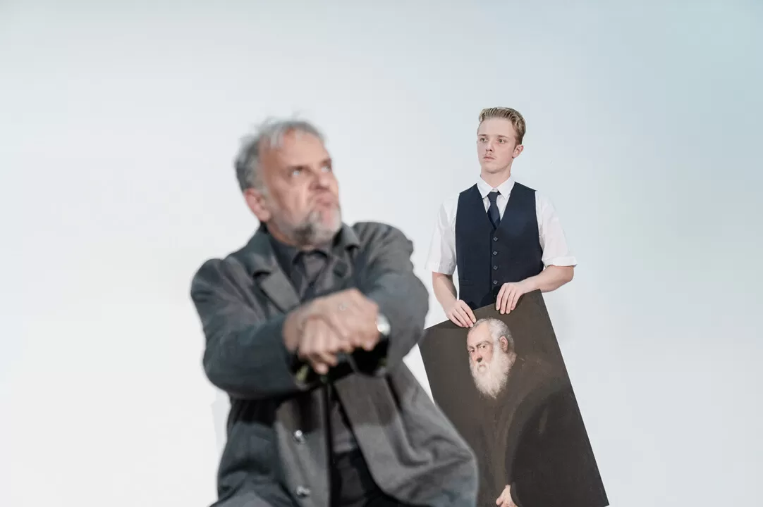 Ein Mann mit Bild in der Hand guckt einen anderen Mann schräg an