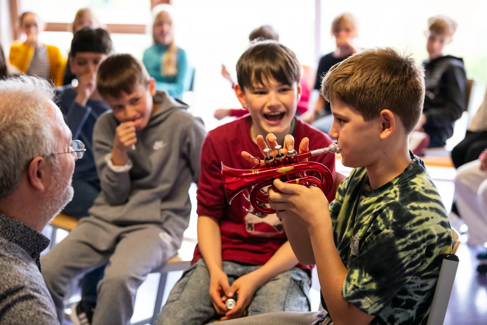 Ein Schüler probiert eine kleine rote Trompete aus.