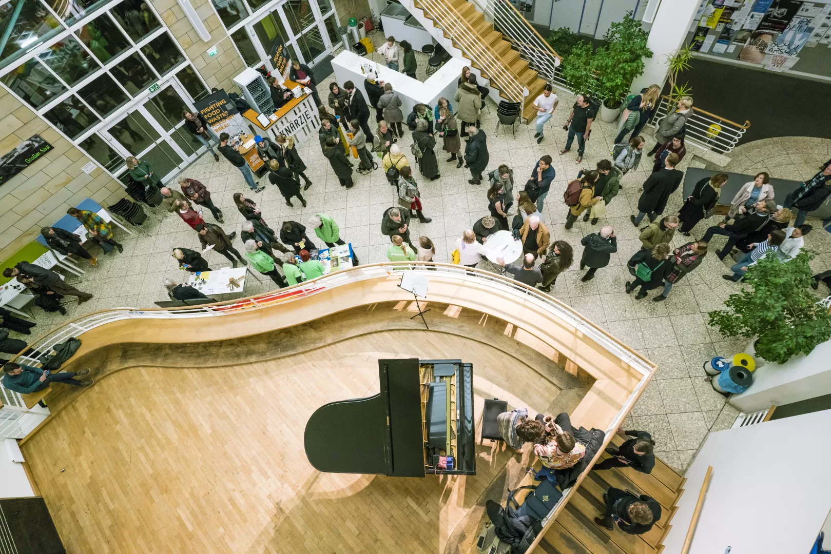 Im Foyer stehen viele Veranstaltungsgäste, auf der Empore vor dem Kleinen Saal steht ein Flügel. Das Bild ist von oben fotografiert.