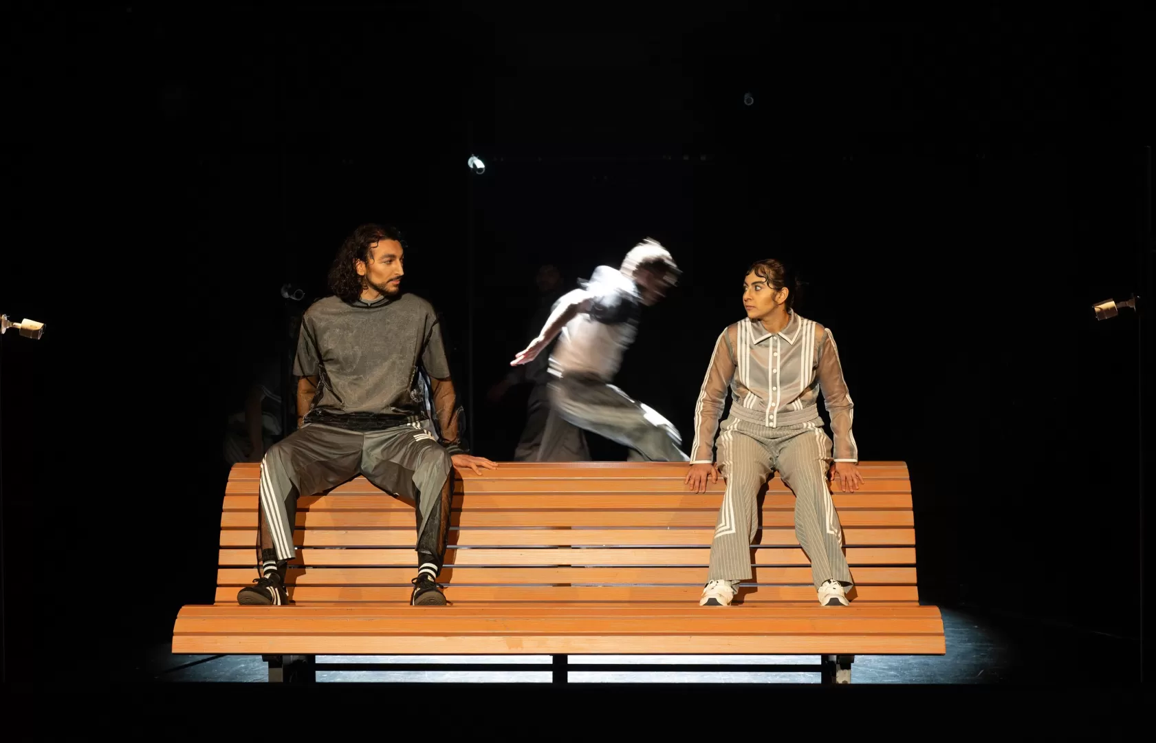 Zwei Leute sitzen auf einer Holzbank und schauen sich an.