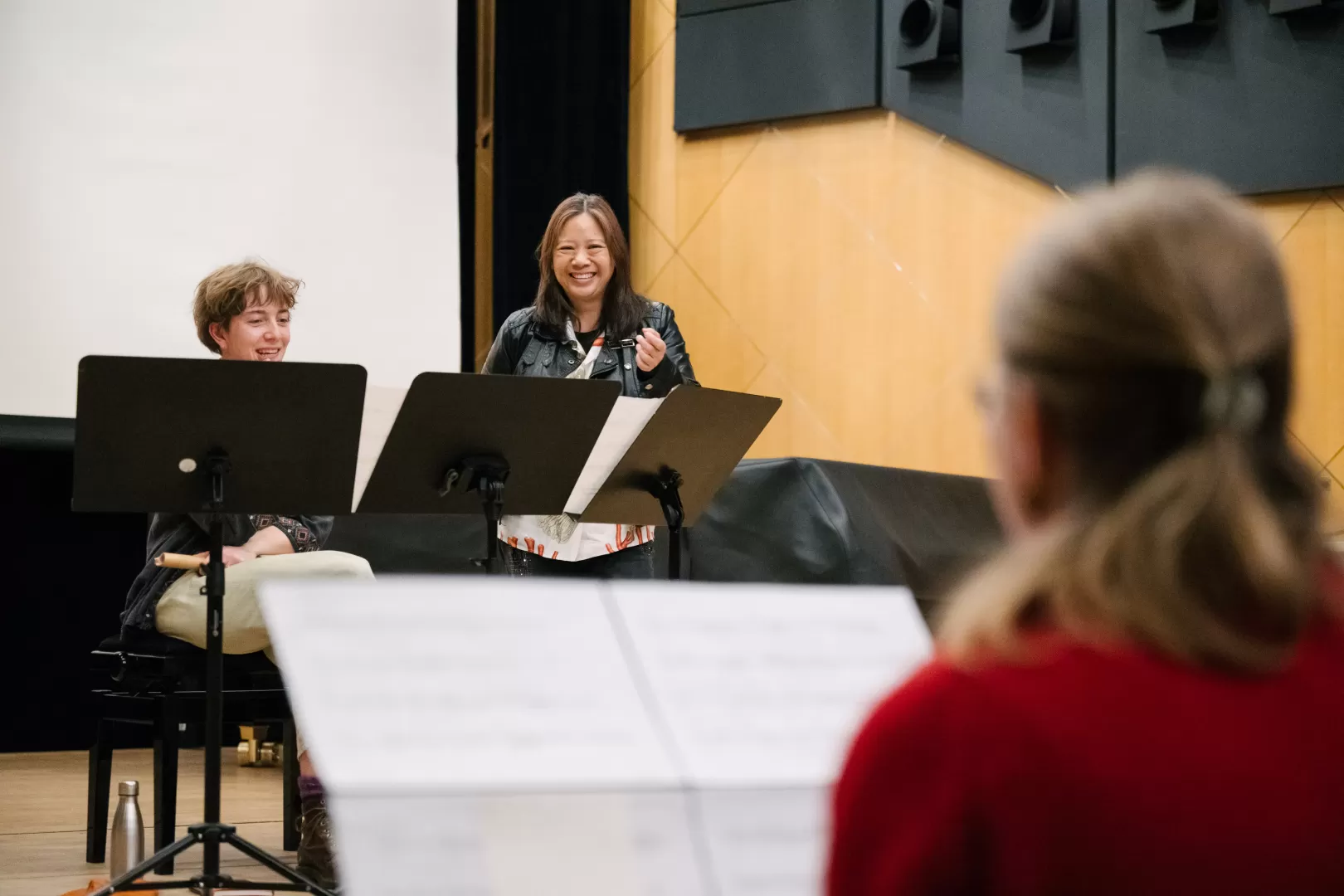 Liza Lim unterrichtet lächelnd zwei Studierende, die hinter ihren Notenpulten sitzen
