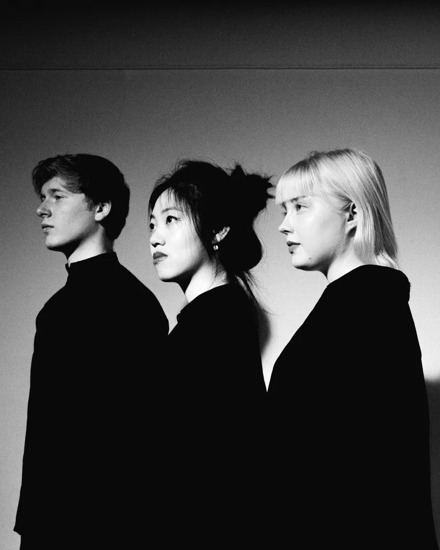 Schwarz-weiß Bild der drei Musiker*innen des Paddington Trios, die alle in die gleiche Richtung blicken