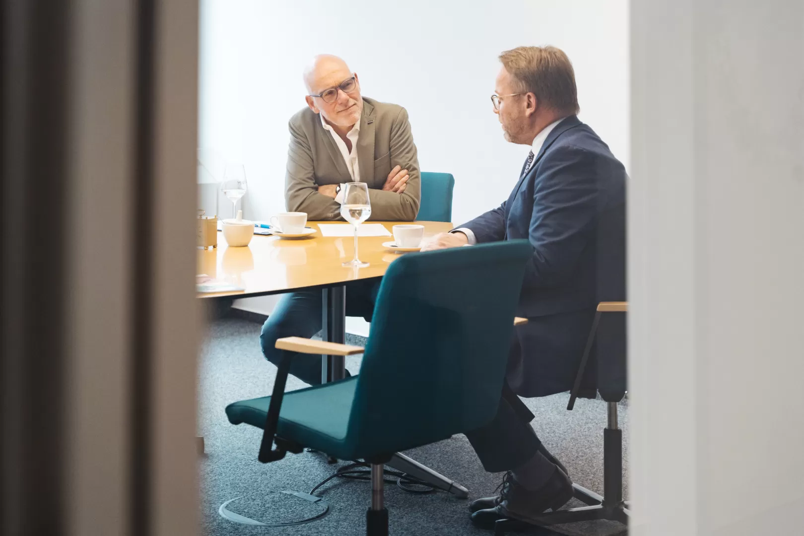 Prof. Elmar Fulda unterhält sich mit Timon Gremmels, durch die Tür des Besprechungsraums fotografiert