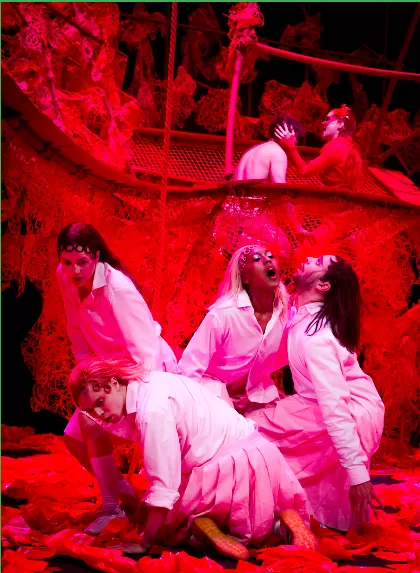 Vier Menschen sitzen beieinander, der Hintergrund ist rot, sie tragen weiße Hemden