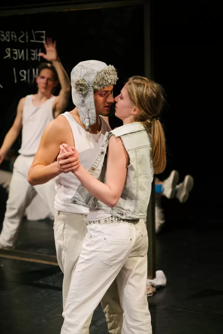 Zwei in weiß gekleidete Menschen küssen sich fast