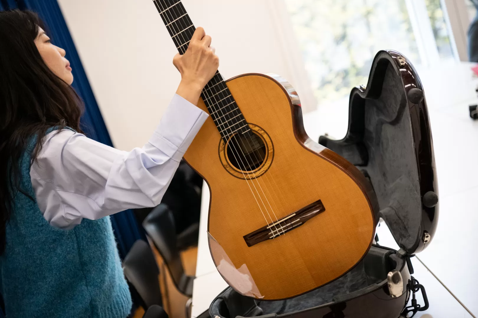 Eine Gitarristin nimmt ihr Instrument aus dem Gitarrenkoffer