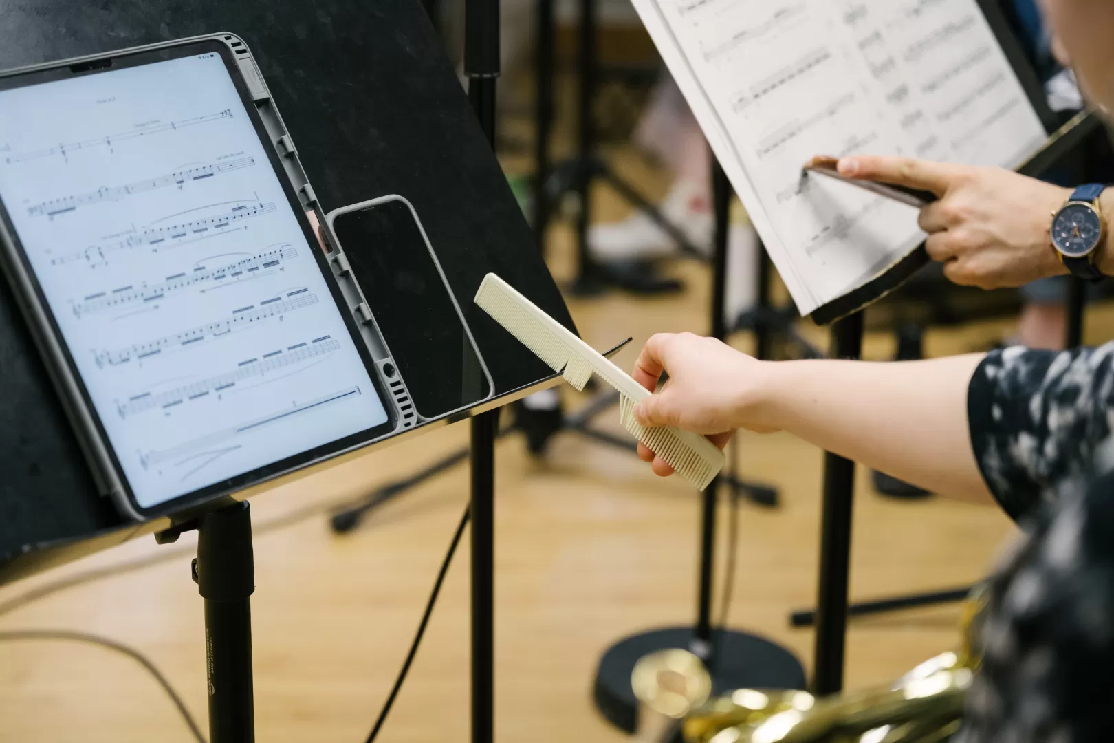 Blick auf ein iPad mit einer zeigtgenössischen Partitur, eine Hand halt daneben einen Kamm aus Plastik