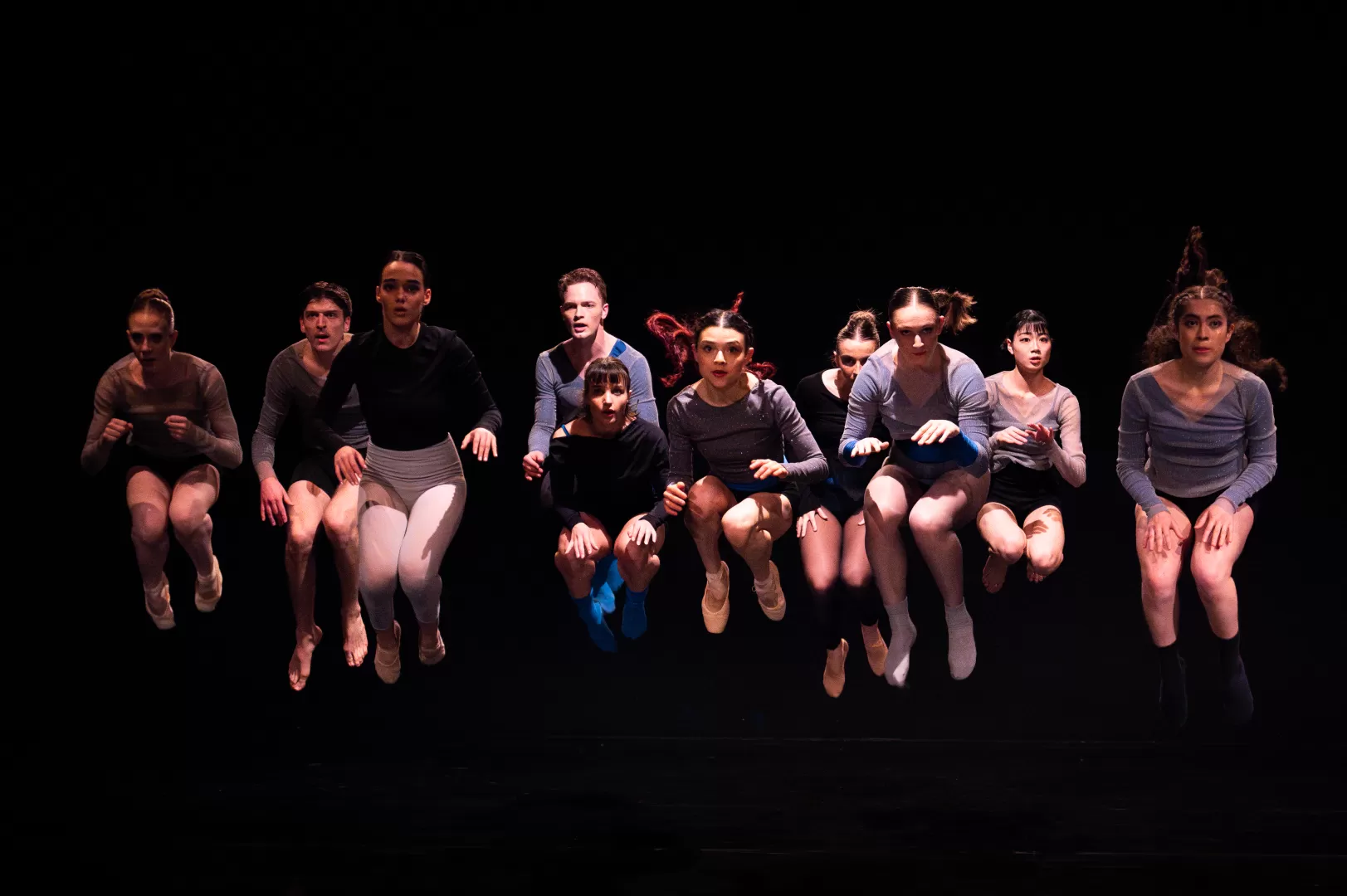 Zehn Tänzer*innen springen in die Luft 