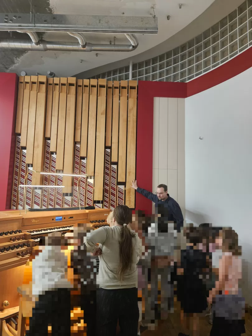 Lukas Euler steht an der Orgel und erklärt, zahlreiche Kinder stehen dicht gedrängt um den Spieltisch herum.