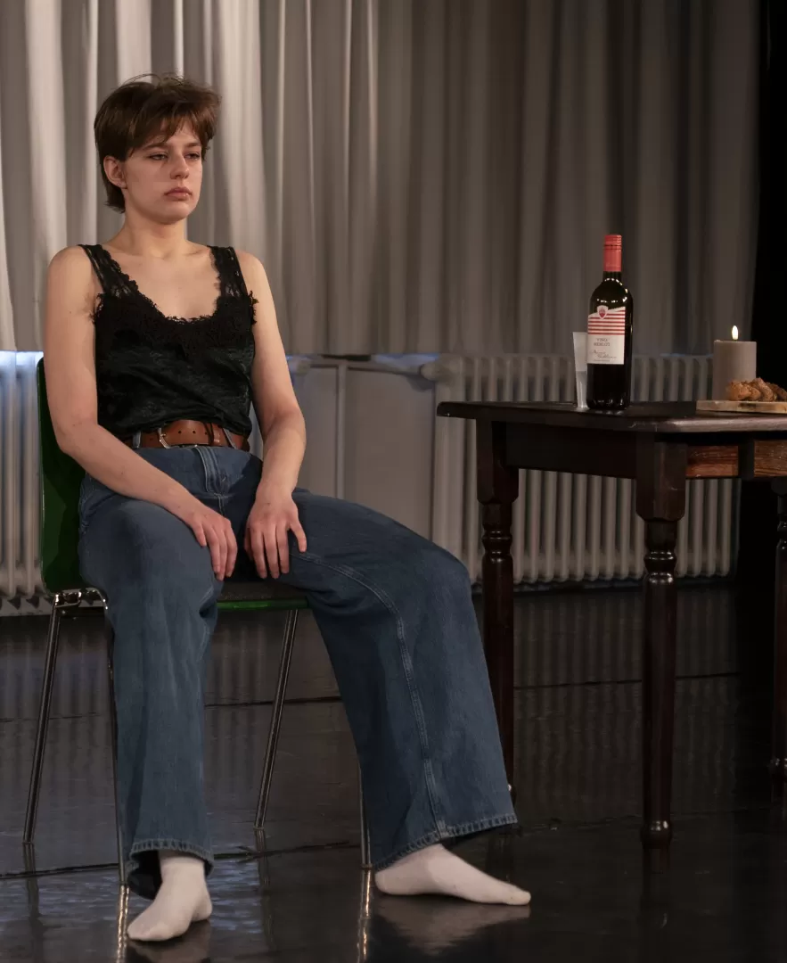 Paula Marie Schulze, Jeans, dunkelgrünes Top, auf einem grünen Stuhl sitzend