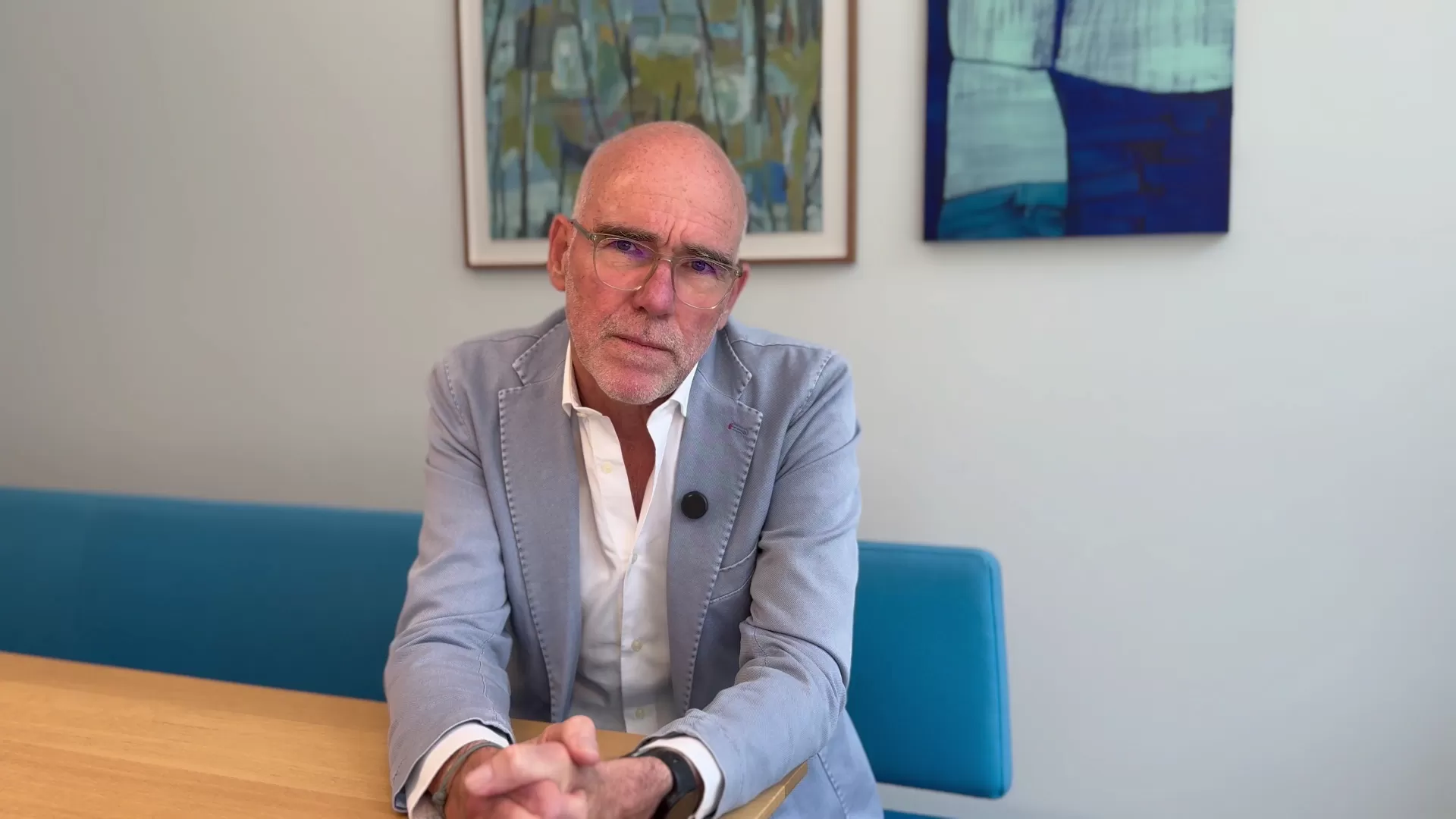 Prof. Fulda trägt ein helles Jackett und sitzt mit gefalteten Händen an einem Tisch, er blickt betroffen in die Kamera.