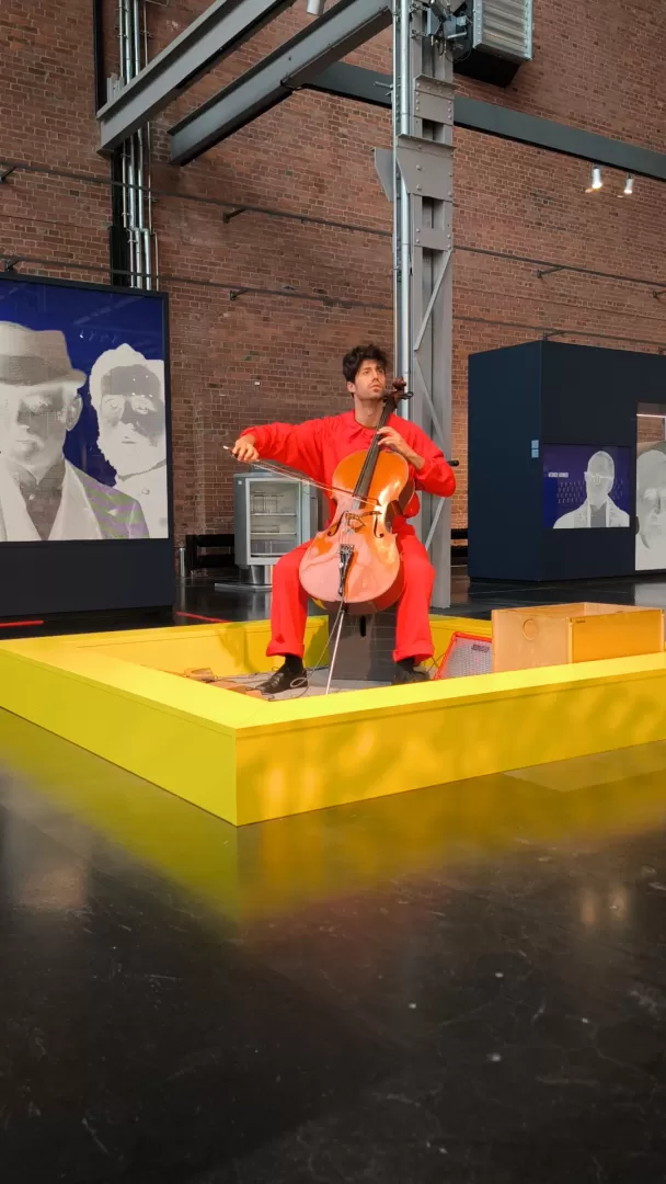 Ein Cellist in einem roten Overall musiziert im Industriemuseum