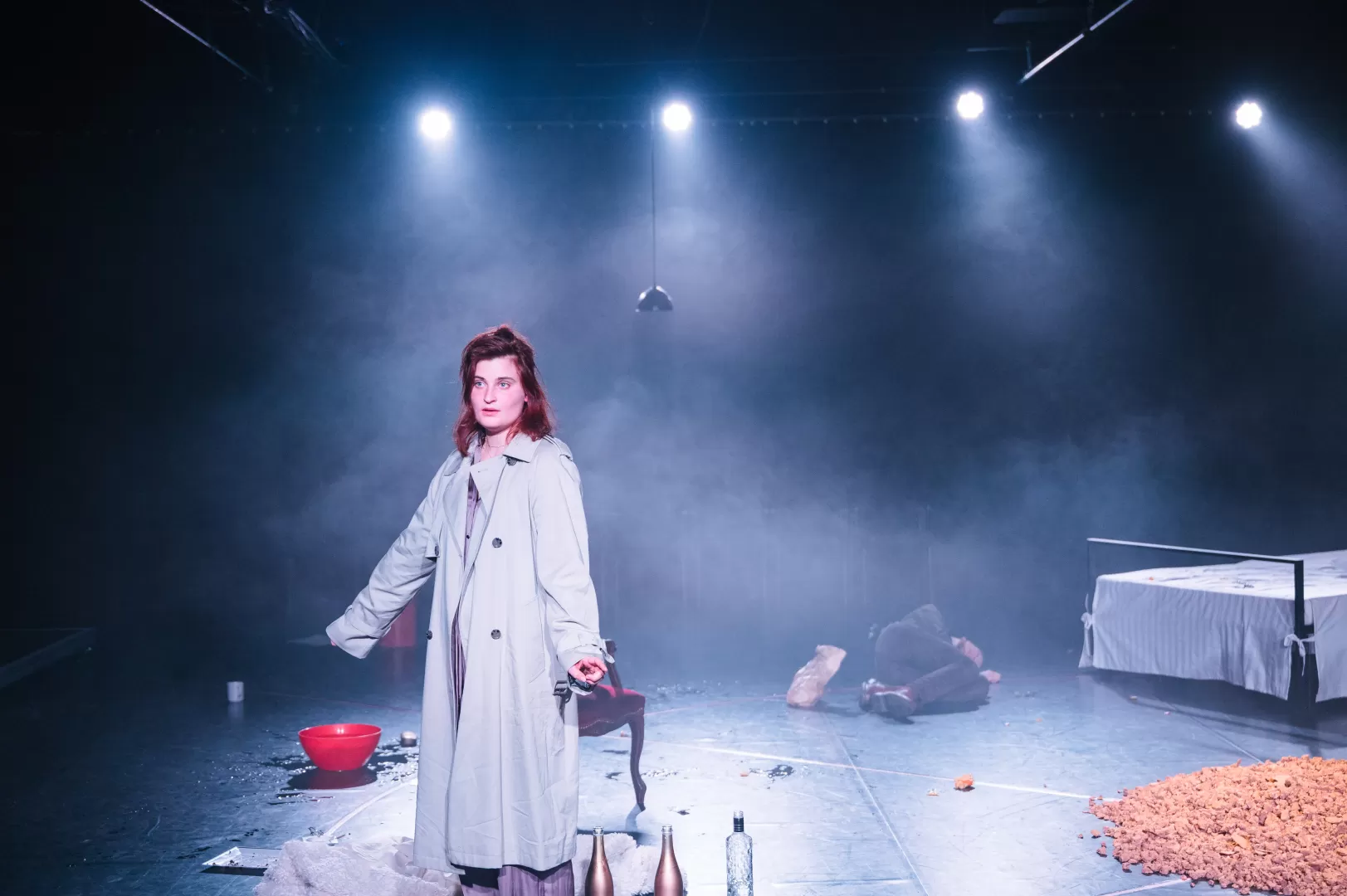 Frau in Mantel steht im Nebel.