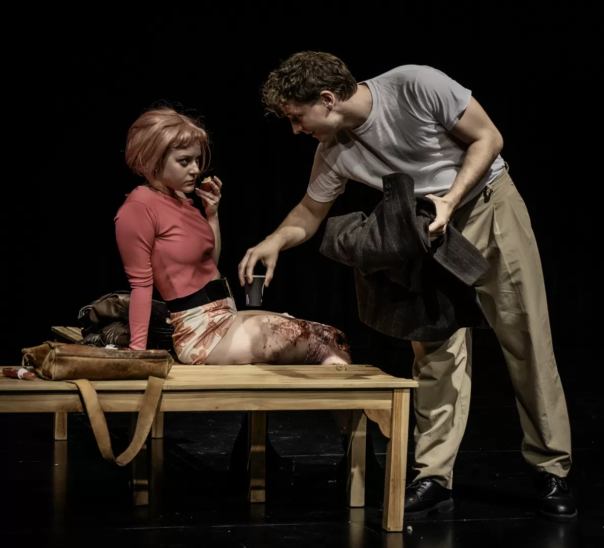 Mann stellt Becher Kaffe auf eine Holzbank.