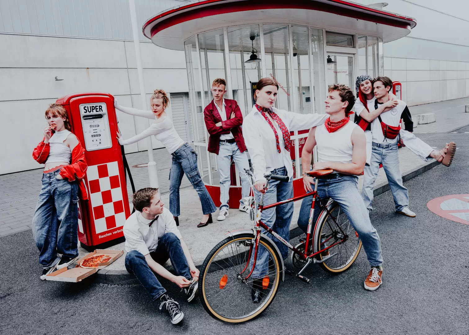 Gruppe von 8 Personen in weißer und roter Kleidung an einer Tankstelle.