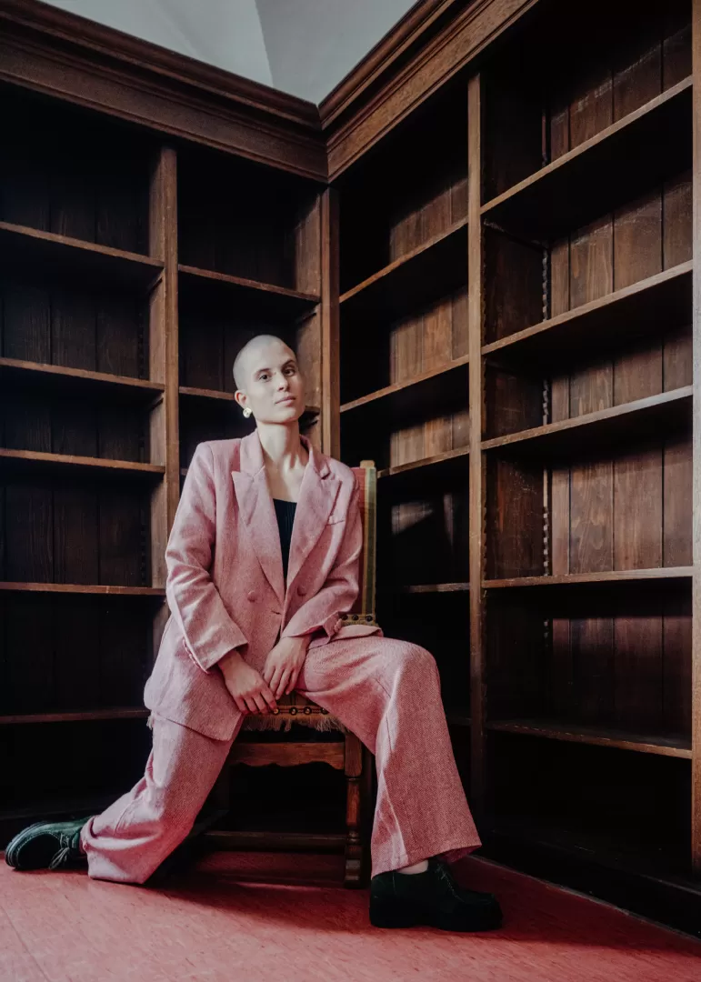 Lisa Freiberger sitzt auf einem Stuhl, sie trägt einen roten Anzug.