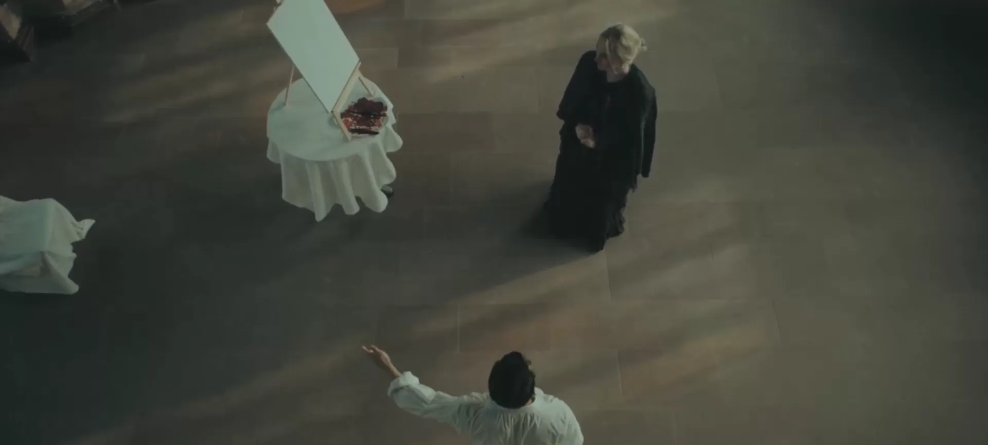 Aus der Vogelperspektive sieht man einen Mann und eine Frau vor einer Kunstleinwand.