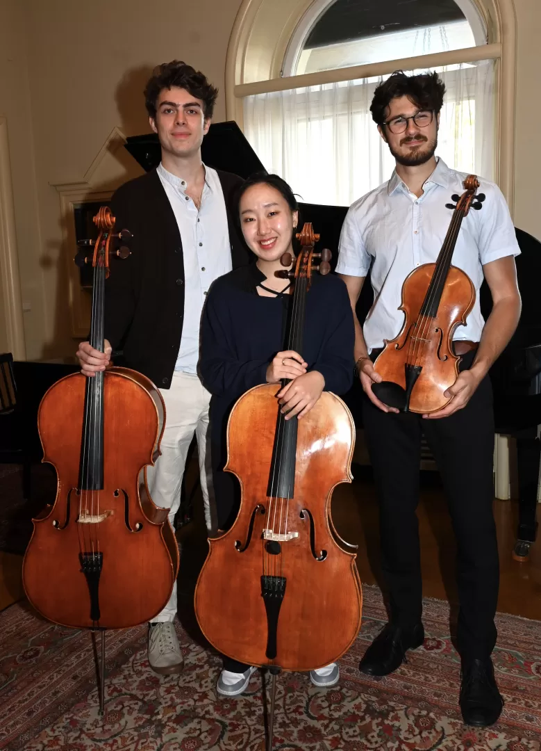 Drei Personen mit ihren Instrumenten - zwei Celli und eine Bratsche - lächeln in die Kamera.