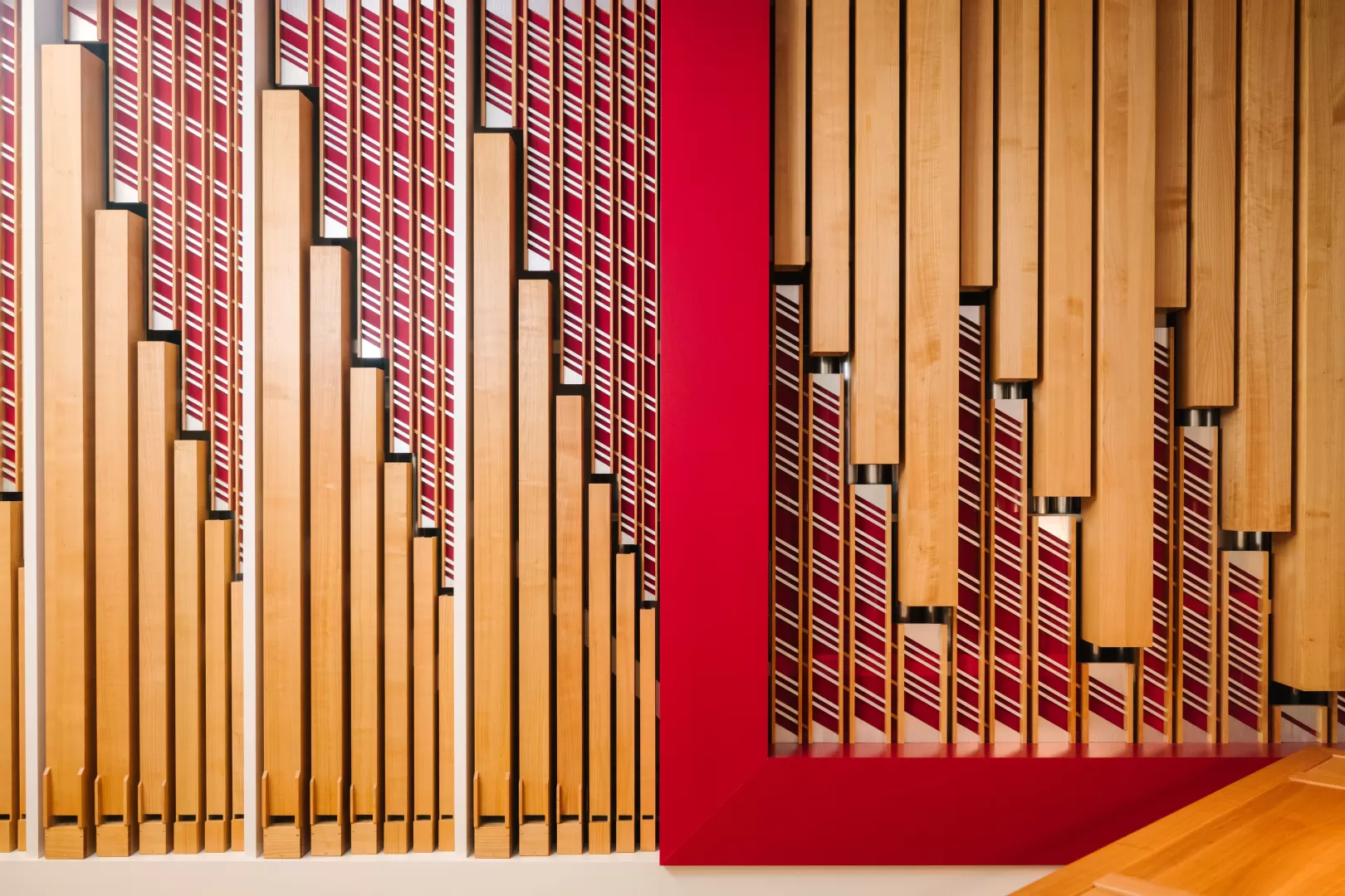 Foto der Rieger Orgel an der HfMDK mit Details in rot und warmen Holztönen