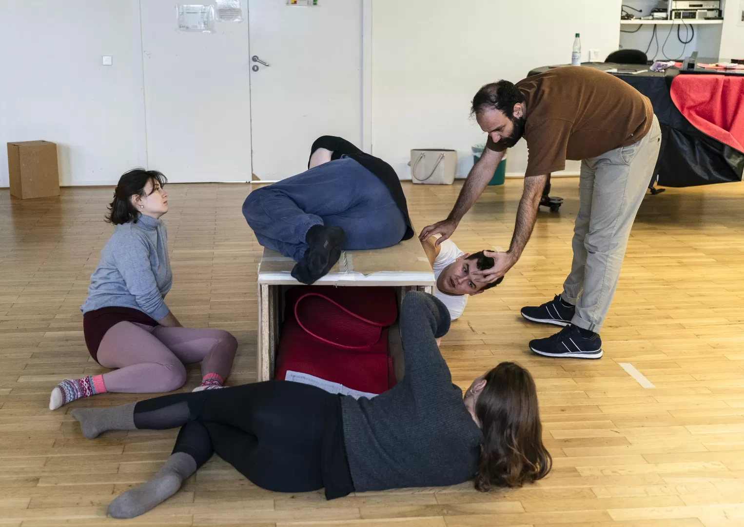 Sänger*innen in einer Szenenprobe liegen um eine Kiste herum