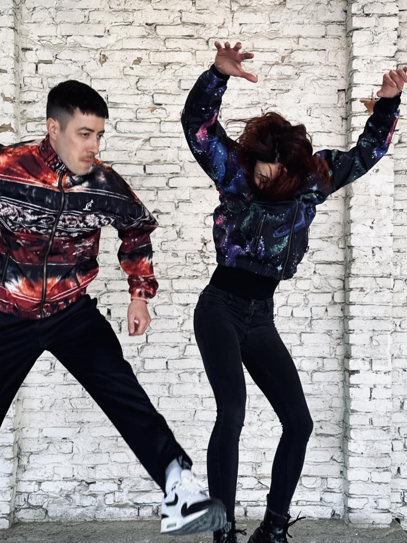 Underground Symphony Eine Frau mit den armen in die Höhe gestreckt und ein Mann im Sprung