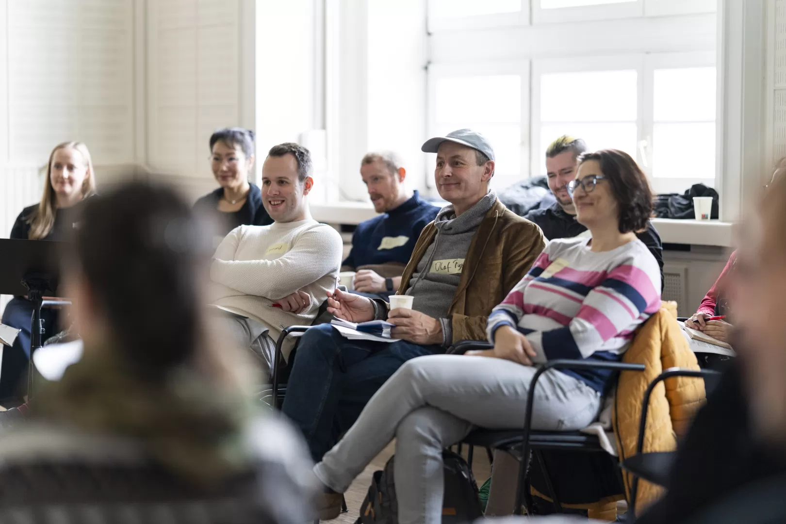 Eine Gruppe der Teilnehmenden sitzt in einem Seminarraum und hört aufmerksam zu