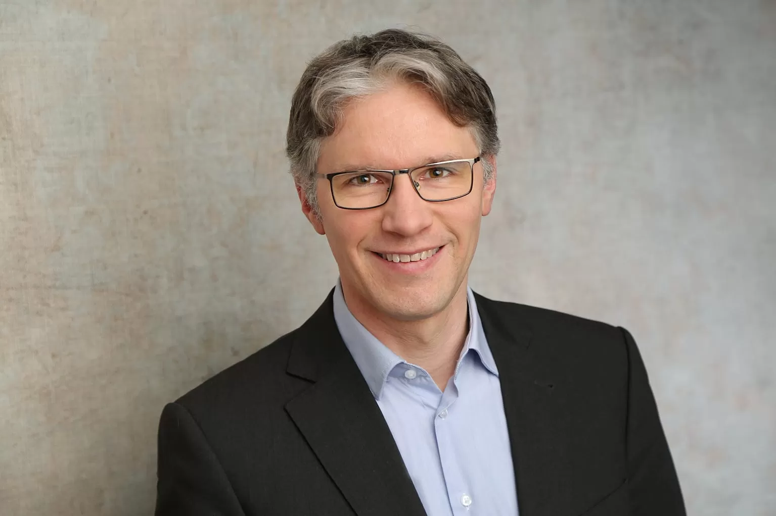 Portraiaufnahme von Jorin Sandau im Anzug vor weißem Hintergrund