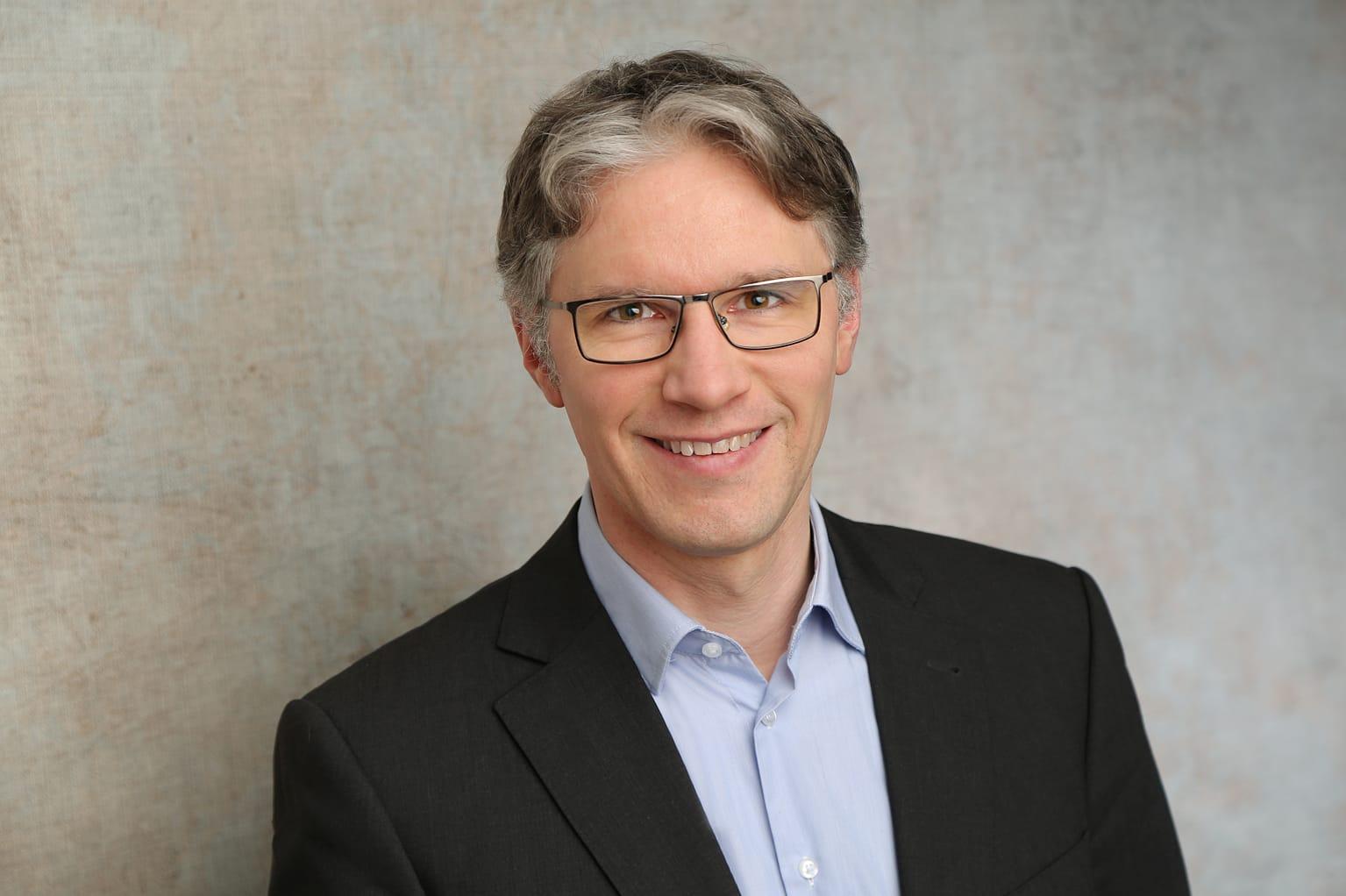 Portraiaufnahme von Jorin Sandau im Anzug vor weißem Hintergrund