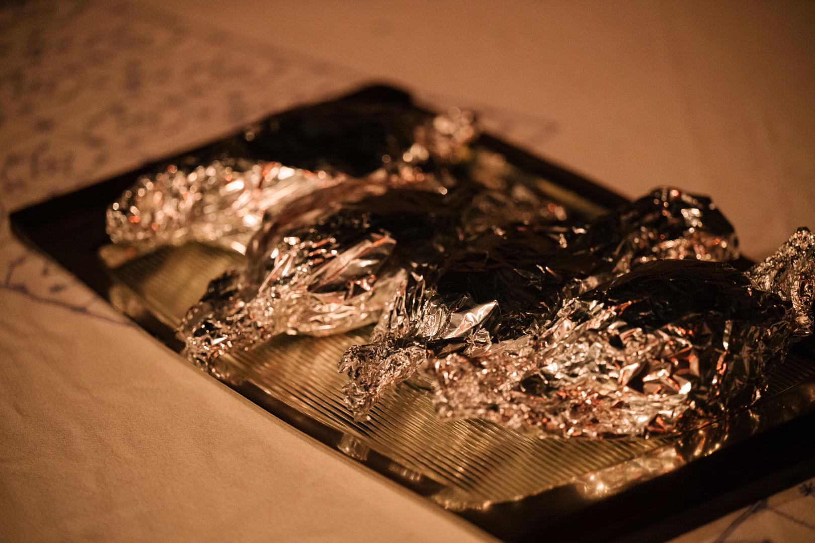 In Alufolie verpacktes Essen auf einem silbernen Tablett.