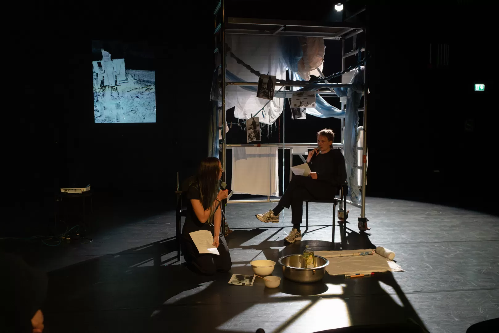 Zwei Personen vor einem Gerüst, dass mit Stoffen behangen ist.