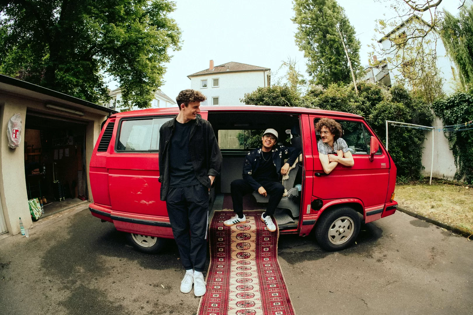 Drei Männer in einem roten Kleintransporter