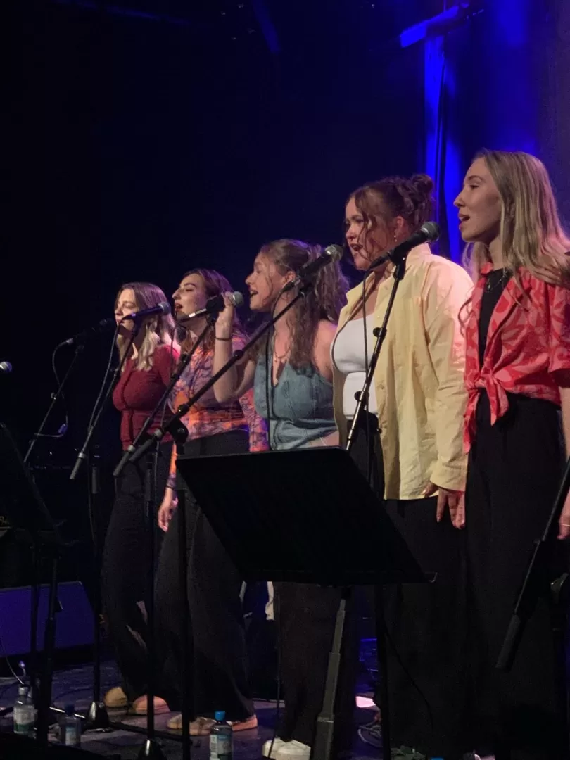 Fünf Frauen singend hinter Mikros auf einer Bühne