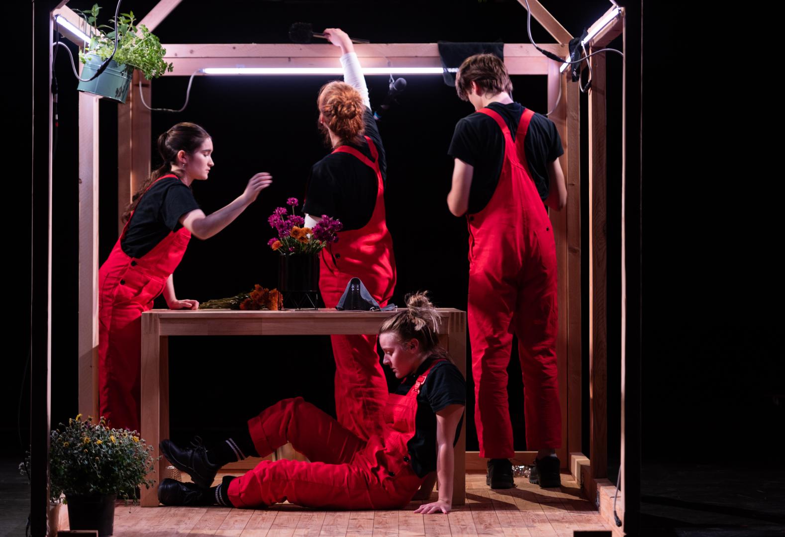 Vier Personen in roten Latzhosen.